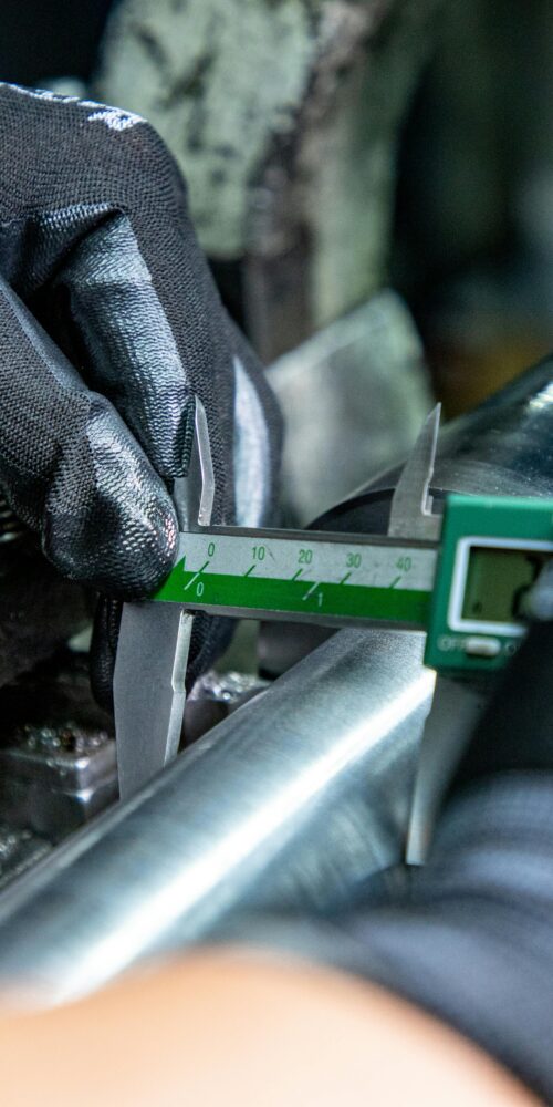 Technician using digital calipers to measure industrial equipment components