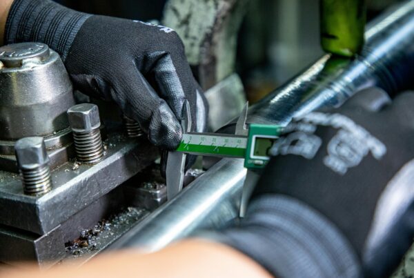 Technician using digital calipers to measure industrial equipment components