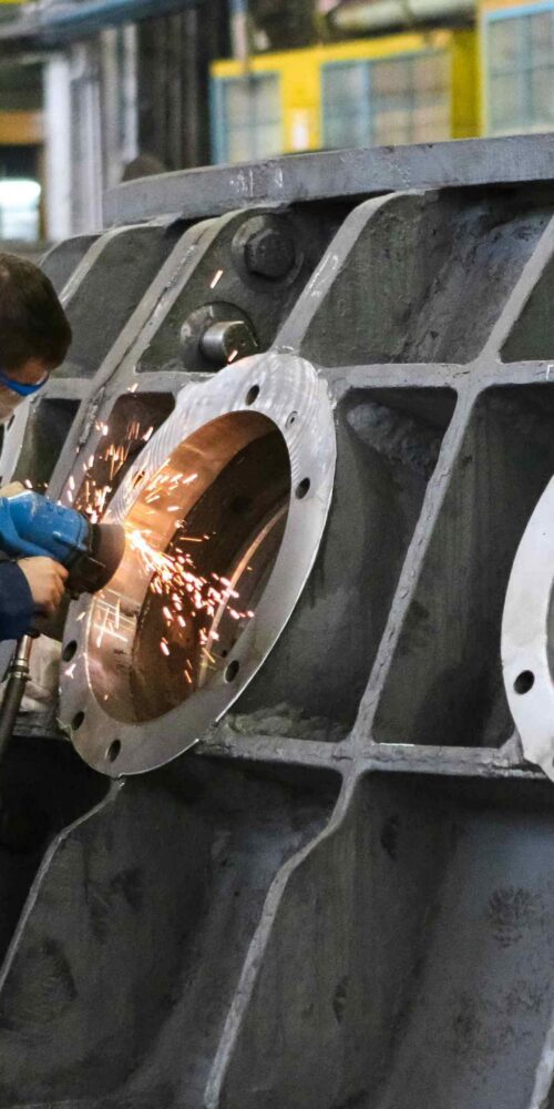 Millwright technician performing precision work on large industrial equipment inside a manufacturing facility