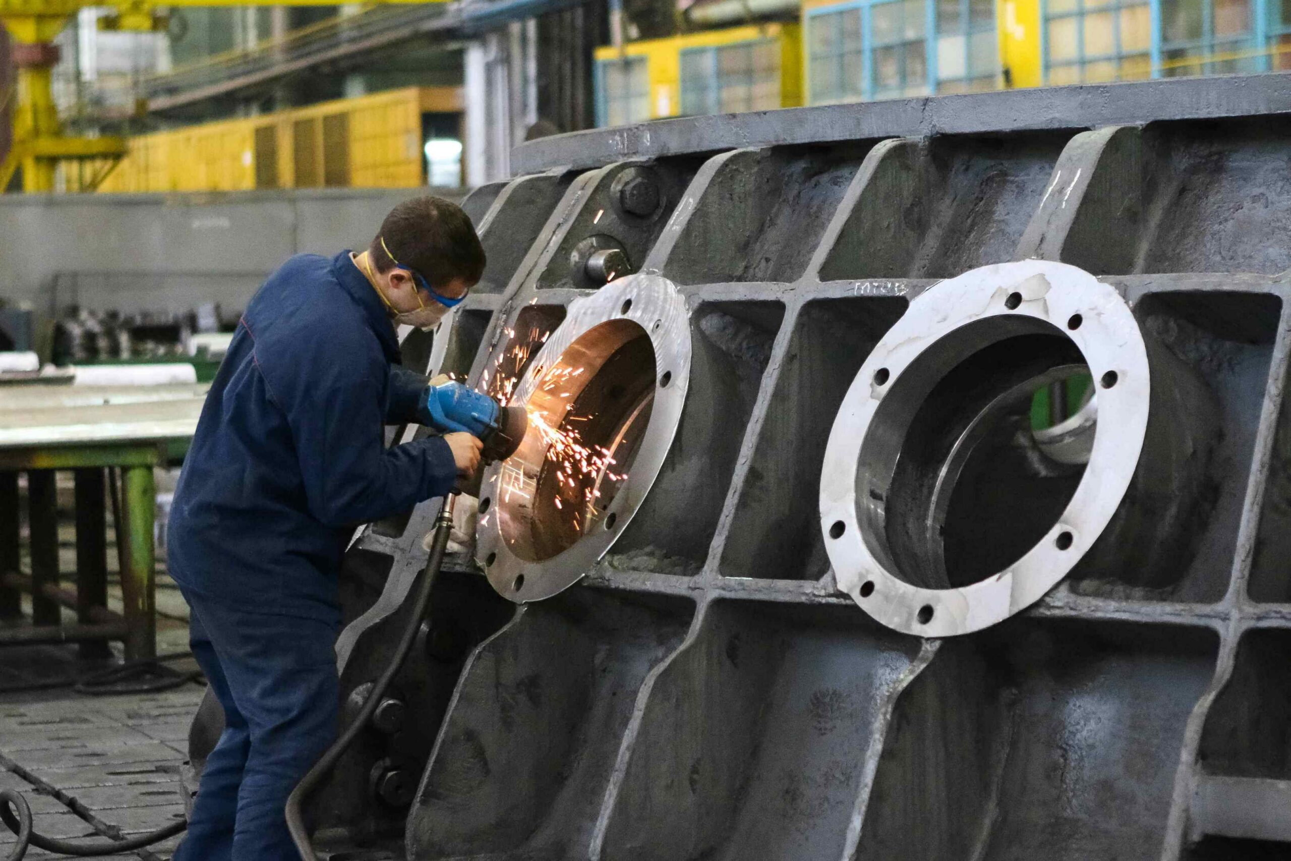 Millwright technician performing precision work on large industrial equipment inside a manufacturing facility